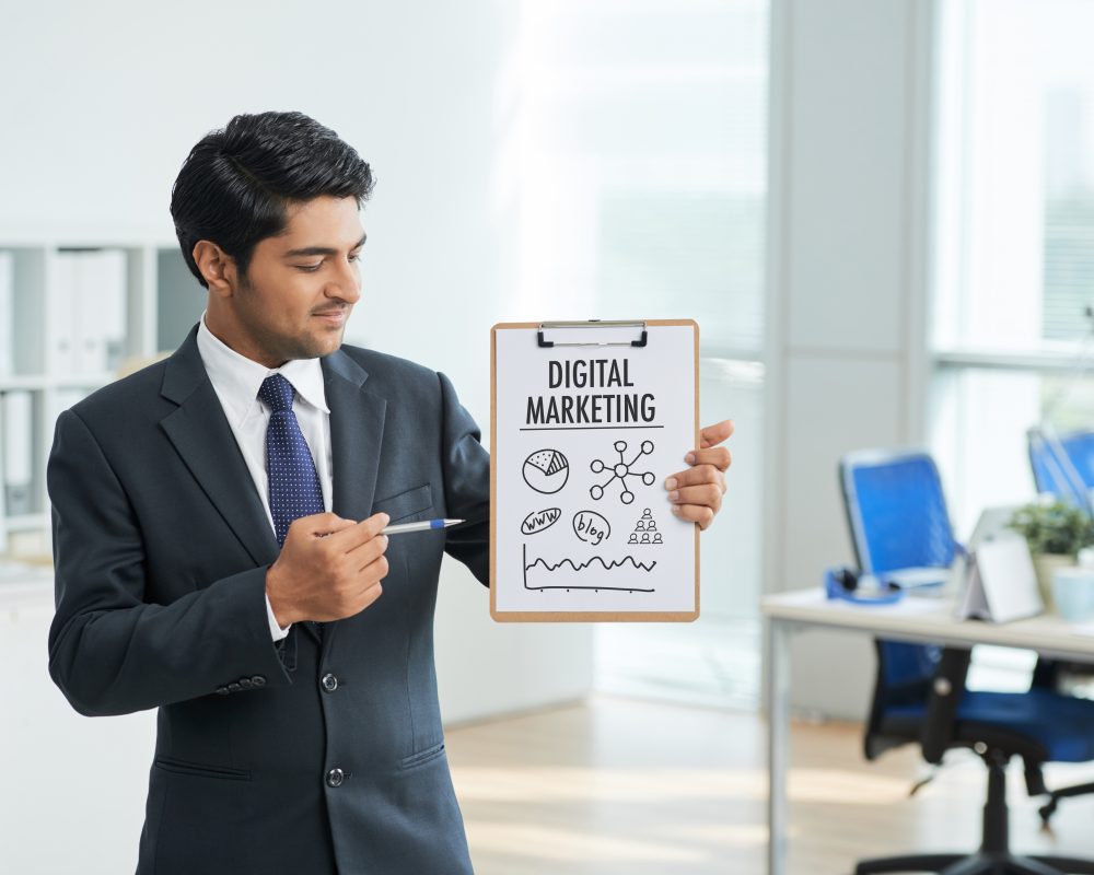 Professional man in office suit presenting digital marketing strategies with clipboard and poster in blog featured image, representing business consultation, strategy development, and marketing planning services by Craze For Marketing Sydney agency.